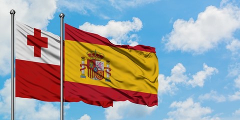 Tonga and Spain flag waving in the wind against white cloudy blue sky together. Diplomacy concept, international relations.