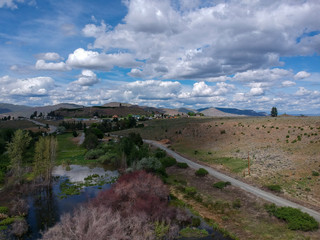 Tremendous aerial photography of picturesque Alta Lake State Park with  an amazing and bright blue sky cumulus clouds reflecting in the water with a semi desert terrain and mountains in washington