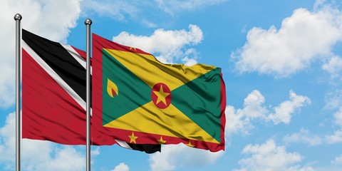 Trinidad And Tobago and Grenada flag waving in the wind against white cloudy blue sky together. Diplomacy concept, international relations.