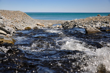 A fresh stream flows into the sea. The coast of the Sea of Okhotsk.