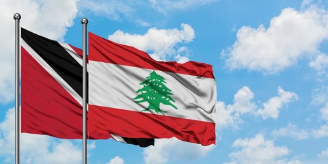 Trinidad And Tobago and Lebanon flag waving in the wind against white cloudy blue sky together. Diplomacy concept, international relations.