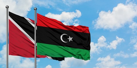 Trinidad And Tobago and Libya flag waving in the wind against white cloudy blue sky together. Diplomacy concept, international relations.