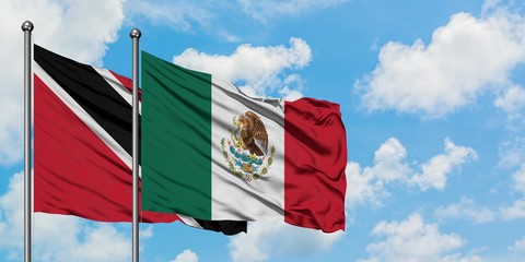 Trinidad And Tobago and Mexico flag waving in the wind against white cloudy blue sky together. Diplomacy concept, international relations.