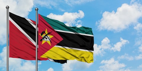 Trinidad And Tobago and Mozambique flag waving in the wind against white cloudy blue sky together. Diplomacy concept, international relations.