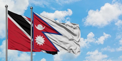 Trinidad And Tobago and Nepal flag waving in the wind against white cloudy blue sky together. Diplomacy concept, international relations.