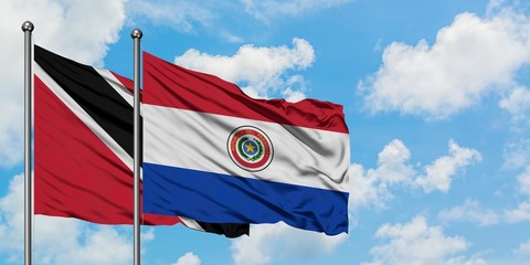 Trinidad And Tobago and Paraguay flag waving in the wind against white cloudy blue sky together. Diplomacy concept, international relations.