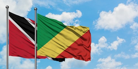 Trinidad And Tobago and Republic Of The Congo flag waving in the wind against white cloudy blue sky together. Diplomacy concept, international relations.