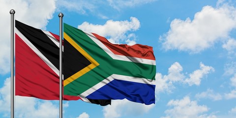 Trinidad And Tobago and South Africa flag waving in the wind against white cloudy blue sky together. Diplomacy concept, international relations.