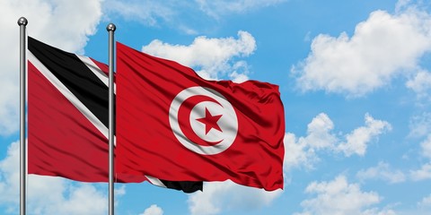 Trinidad And Tobago and Tunisia flag waving in the wind against white cloudy blue sky together. Diplomacy concept, international relations.