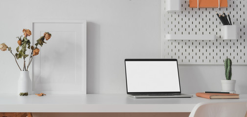 Modern workspace with open blank screen laptop computer and mock up frame with decorations