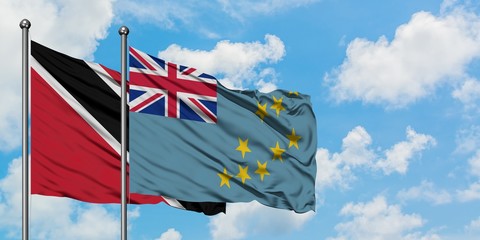 Trinidad And Tobago and Tuvalu flag waving in the wind against white cloudy blue sky together. Diplomacy concept, international relations.