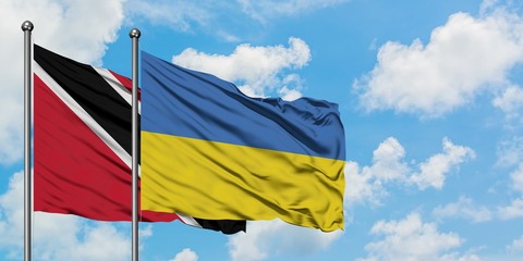 Trinidad And Tobago and Ukraine flag waving in the wind against white cloudy blue sky together. Diplomacy concept, international relations.