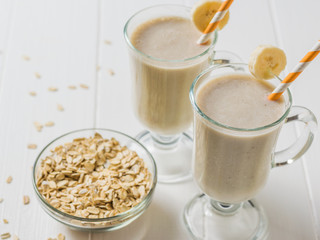 Banana smoothie with oatmeal in glasses on a white table. Vegetarian smoothie.