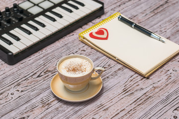A music mixer, a Cup of coffee and a notebook on a wooden table.