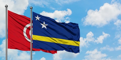 Tunisia and Curacao flag waving in the wind against white cloudy blue sky together. Diplomacy concept, international relations.