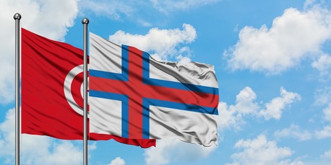 Tunisia and Faroe Islands flag waving in the wind against white cloudy blue sky together. Diplomacy concept, international relations.