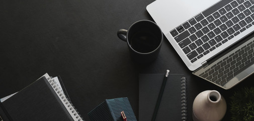 Overhead shot of dark modern office room with laptop computer and coffee cup