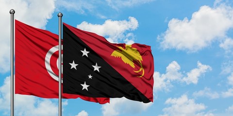 Tunisia and Papua New Guinea flag waving in the wind against white cloudy blue sky together. Diplomacy concept, international relations.