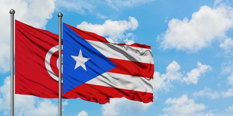 Tunisia and Puerto Rico flag waving in the wind against white cloudy blue sky together. Diplomacy concept, international relations.