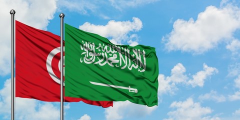 Tunisia and Saudi Arabia flag waving in the wind against white cloudy blue sky together. Diplomacy concept, international relations.
