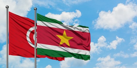 Tunisia and Suriname flag waving in the wind against white cloudy blue sky together. Diplomacy concept, international relations.