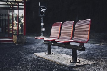 Three red seats in the bus station of an urban area - obrazy, fototapety, plakaty