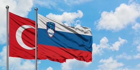 Turkey and Slovenia flag waving in the wind against white cloudy blue sky together. Diplomacy concept, international relations.