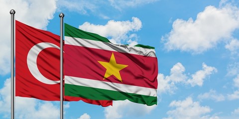 Turkey and Suriname flag waving in the wind against white cloudy blue sky together. Diplomacy concept, international relations.