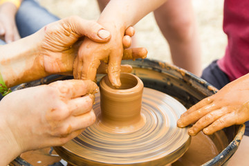 A close up view on ceramic production process on potter's wheel with children. Clay crafts with kids concept.
