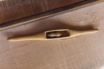 Wooden Shuttle and Spool on cotton thread in Loom. Weaving shuttle on the cotton fabric. Weaving...