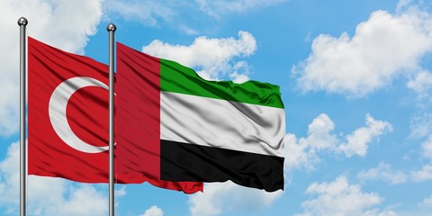 Turkey and United Arab Emirates flag waving in the wind against white cloudy blue sky together. Diplomacy concept, international relations.