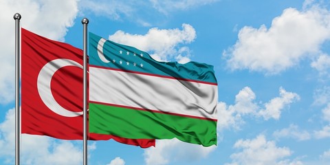Turkey and Uzbekistan flag waving in the wind against white cloudy blue sky together. Diplomacy concept, international relations.