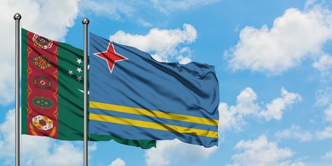 Turkmenistan and Aruba flag waving in the wind against white cloudy blue sky together. Diplomacy concept, international relations.