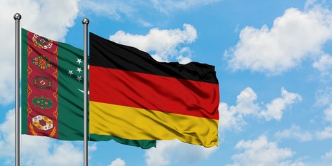 Turkmenistan and Germany flag waving in the wind against white cloudy blue sky together. Diplomacy concept, international relations.