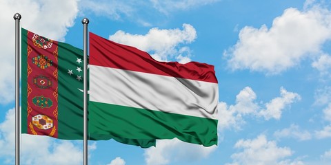 Turkmenistan and Hungary flag waving in the wind against white cloudy blue sky together. Diplomacy concept, international relations.