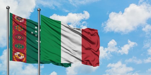 Turkmenistan and Italy flag waving in the wind against white cloudy blue sky together. Diplomacy concept, international relations.