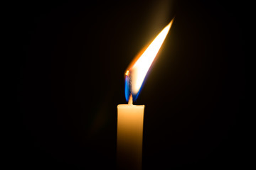 One candle light illuminated in a black background.