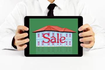 Businessman holding a tablet with house and red word sale