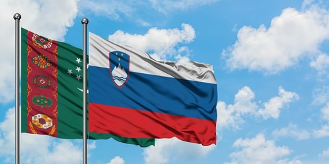 Turkmenistan and Slovenia flag waving in the wind against white cloudy blue sky together. Diplomacy concept, international relations.
