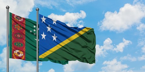 Turkmenistan and Solomon Islands flag waving in the wind against white cloudy blue sky together. Diplomacy concept, international relations.