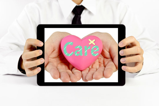 Businessman holding a tablet with heart and write the word care