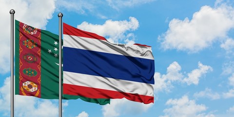 Turkmenistan and Thailand flag waving in the wind against white cloudy blue sky together. Diplomacy concept, international relations.