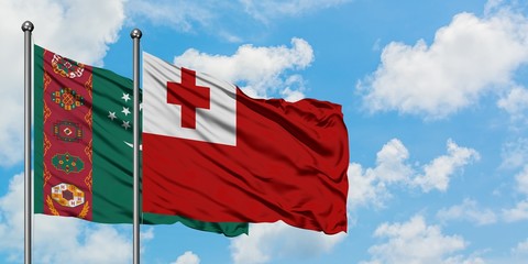 Turkmenistan and Tonga flag waving in the wind against white cloudy blue sky together. Diplomacy concept, international relations.