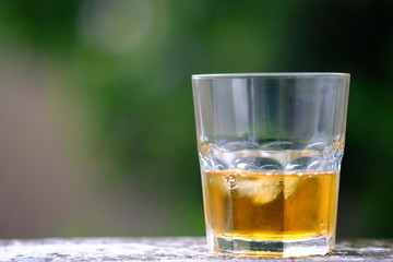 glass of whiskey and ice on wooden table