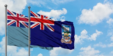 Tuvalu and Falkland Islands flag waving in the wind against white cloudy blue sky together....