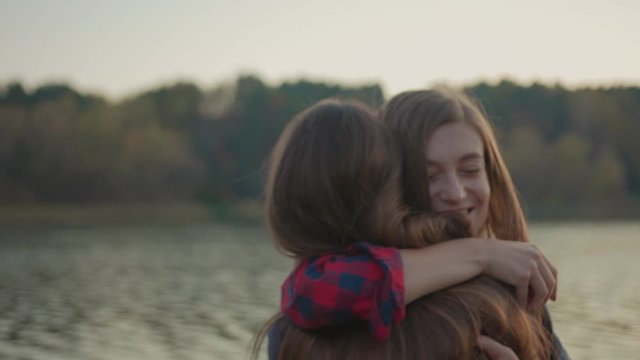 Adorable couple of affectionate happy women hugging tight celebrating exciting event marriage proposal at beautiful lake in nature countryside. Just married. Love confession.