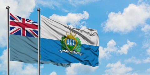 Tuvalu and San Marino flag waving in the wind against white cloudy blue sky together. Diplomacy...