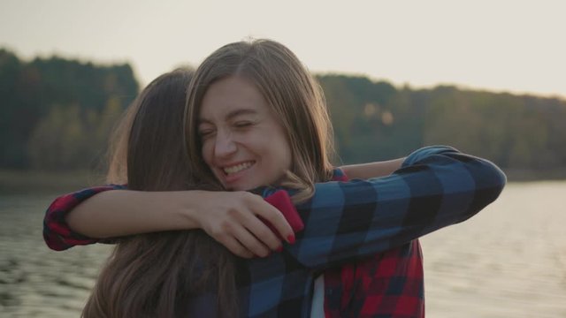 Just married happy woman hugging her girlfriend holding engagement ring crying of happiness exciting love moments on the river bank. Marriage proposal in nature.