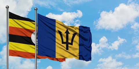 Uganda and Barbados flag waving in the wind against white cloudy blue sky together. Diplomacy concept, international relations.