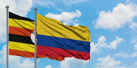 Uganda and Colombia flag waving in the wind against white cloudy blue sky together. Diplomacy concept, international relations.